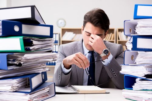 A man at a desk between stacks of binders
