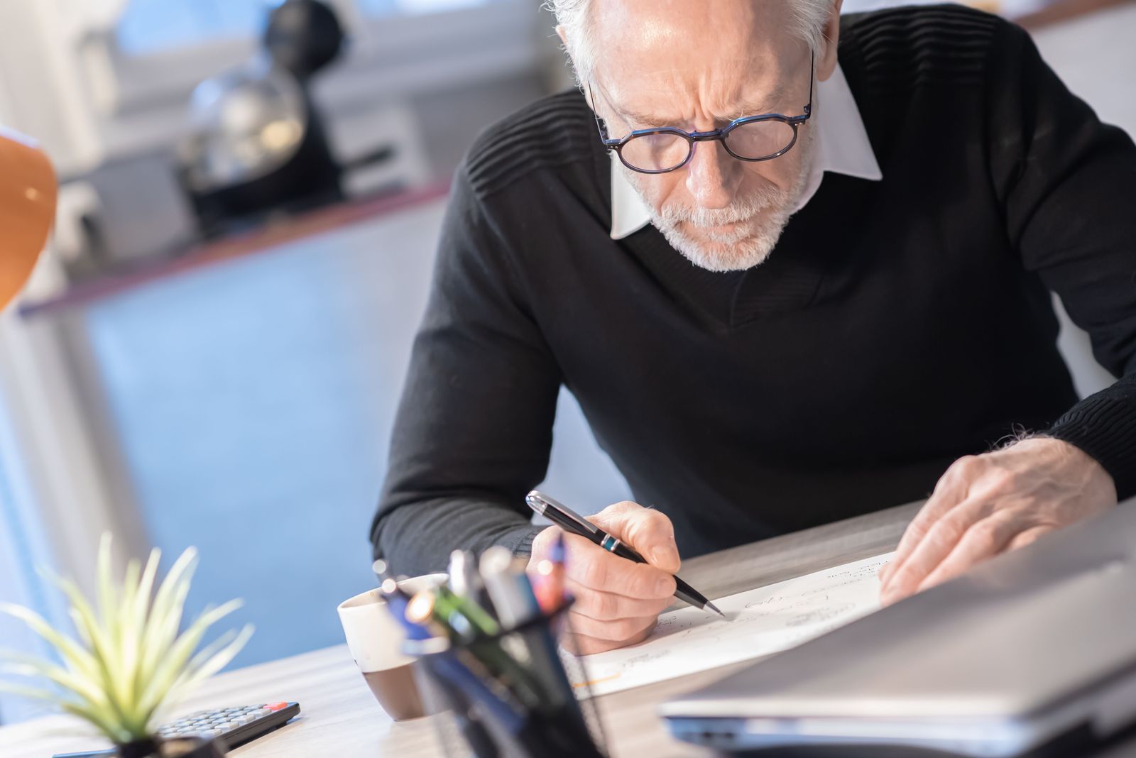 An older man writing at a desk